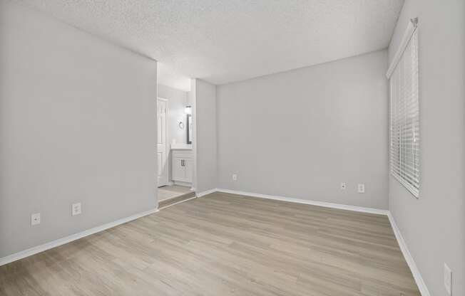 an empty living room with wood flooring and white walls