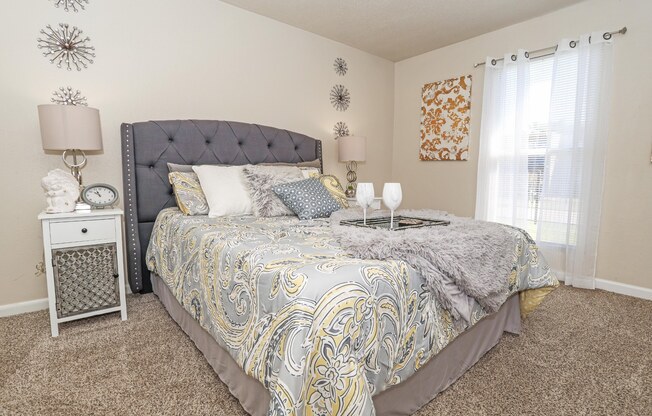 A bedroom with a bed, nightstand, and wall decorations at The Drake in Bossier City, LA