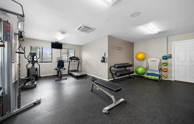 24-hour fitness center at cardio machines and weights at Woodland Villa Apartments in Westland, MI.