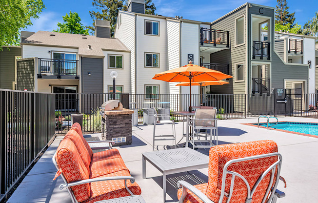 A patio with chairs and an umbrella in front of apartment buildings.