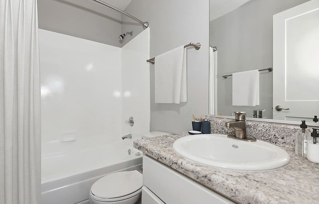 Model Bathroom with Wood-Style Flooring and Shower/Tub at Stillwater Apartments in Glendale, AZ.