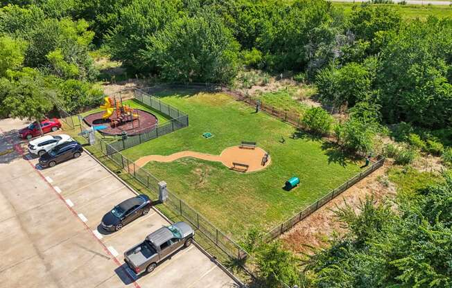 a park with a playground and cars parked in a parking lot