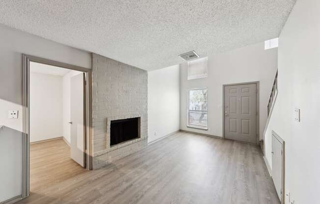 the living room and dining room of an apartment with a fireplace