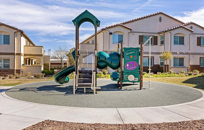 A playground with a green slide and a sign that says "Kids Play Area".