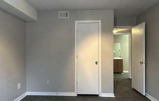 an empty living room with a hallway to a closet and a door to a bathroom