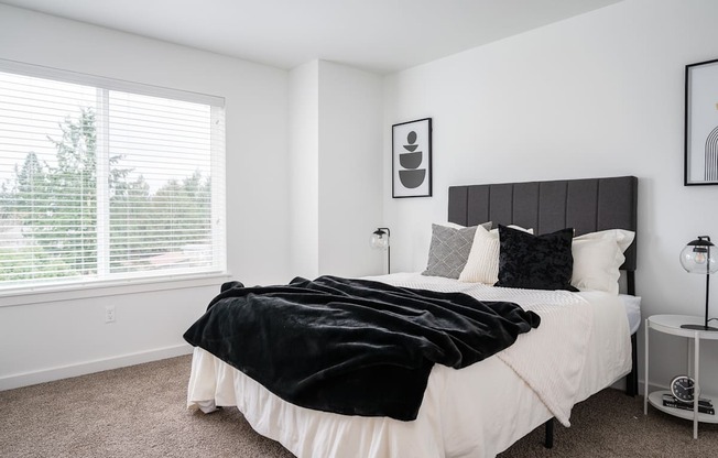 a bedroom with white walls and a large window with blinds