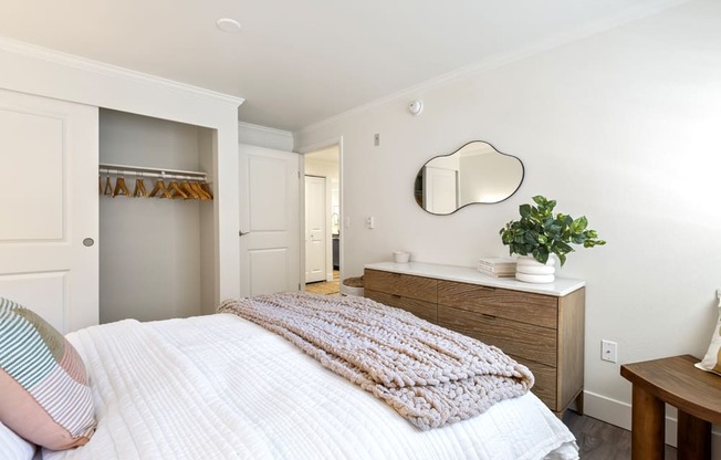 a bedroom with a white bed and a mirror on the wall