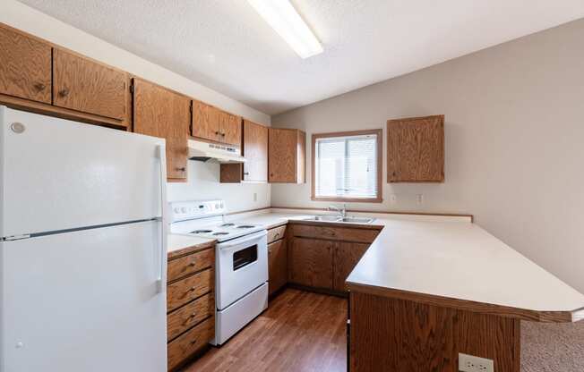 an updated kitchen with white appliances and wooden cabinets. Fargo, ND Rosegate Apartments