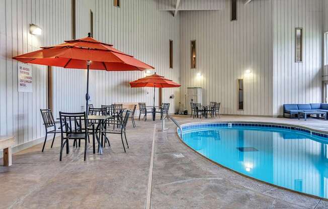 A large indoor swimming pool with a table and chairs around it.