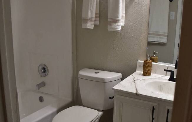 a bathroom with a toilet and a tub and a sink at Ivy Plains at Brooks Apartments, Texas, 78223