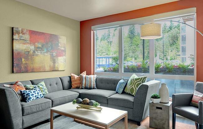 A living room with a grey couch, a coffee table, and a painting on the wall. at Kirkland Crossing Apartments, Kirkland, Washington