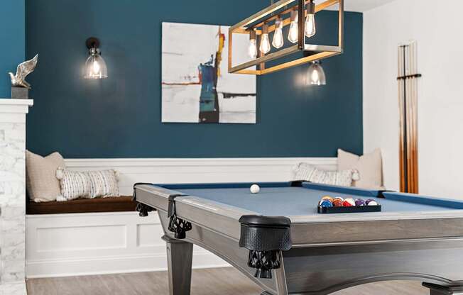 A pool table with a lighted billiard light above it.