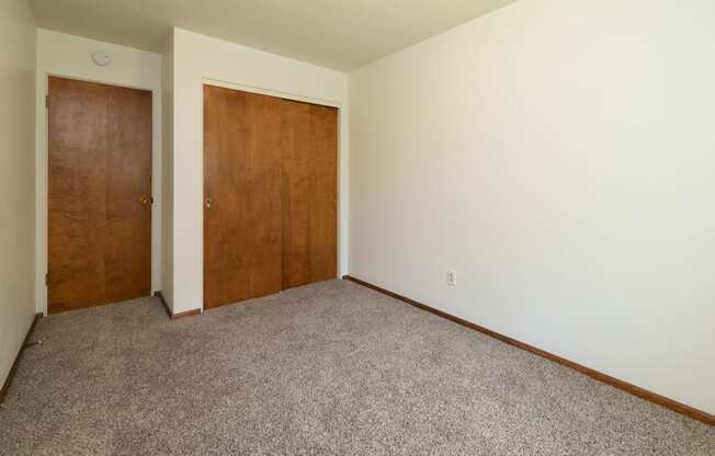 a bedroom with a closet and a door to a hallway. Fargo, ND Islander Apartments