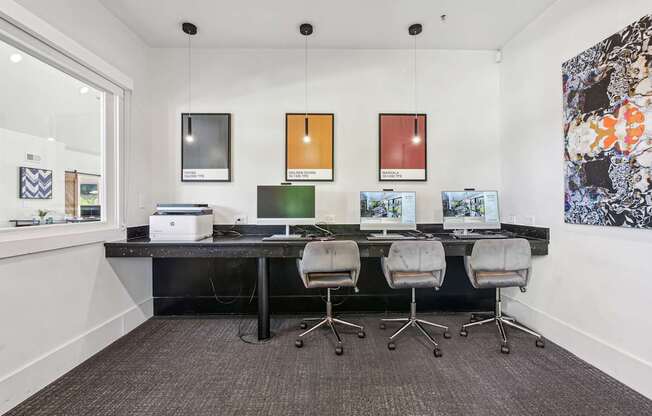 A modern office with a long desk and four chairs.
