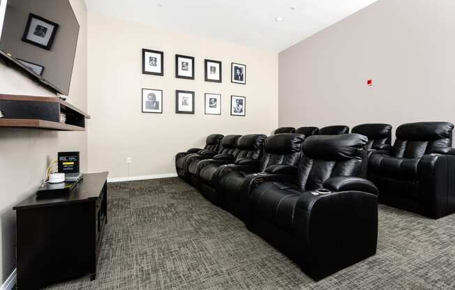 theater room with tv and leather chairs