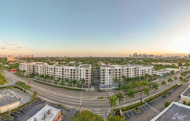 an aerial view of an empty parking lot with apartment buildings and a city skyline