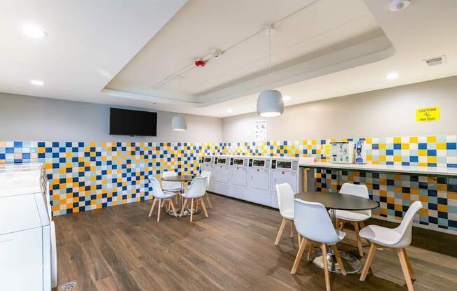 A kitchen with a white washing machine and a tiled wall.
