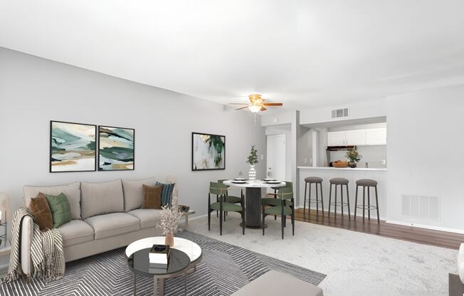 a living room with a couch a table and a chair and a kitchen in the background at Lakes Edge Apartments, Greensboro, North Carolina