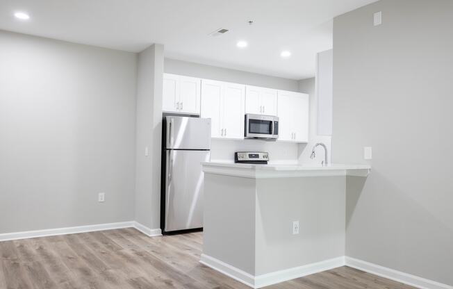 a kitchen with white cabinets and a stainless steel refrigerator