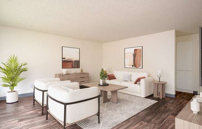 A living room with a white couch, a white chair, a white coffee table, a white rug, and a white plant.