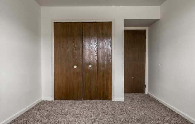 a bedroom with two closet doors and a carpet floor