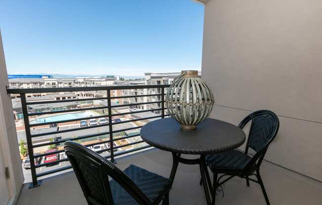 a balcony with a table and chairs and a view of the city