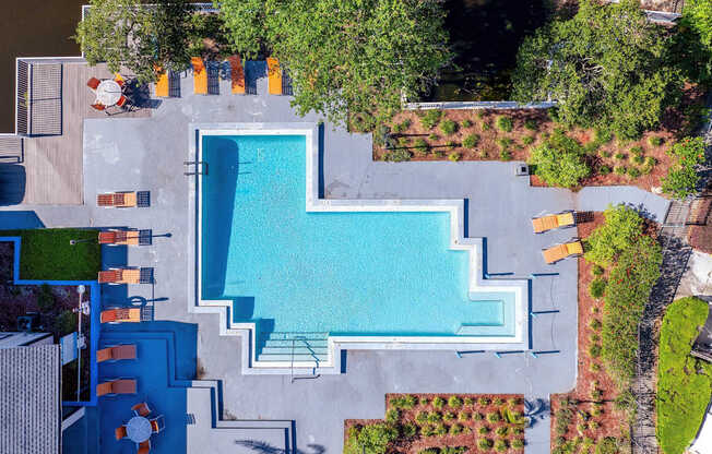 A swimming pool surrounded by a concrete patio and a green lawn.