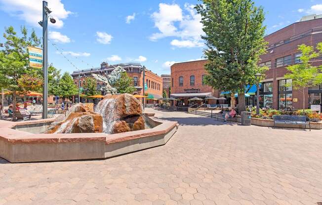 A fountain in the middle of a plaza with people sitting around it.