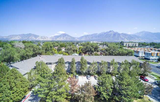 an aerial view of a building with trees and mountains in the background