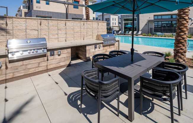 A table with chairs and an umbrella is on a patio.