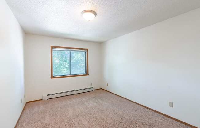 the living room of an empty house with a window. Fargo, ND Rosegate Apartments