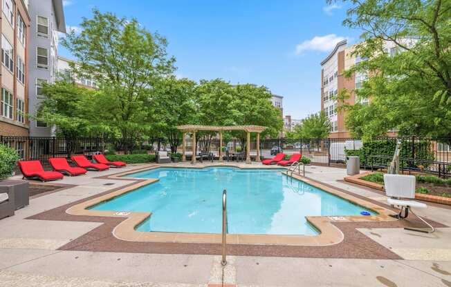 A swimming pool surrounded by trees and chairs.