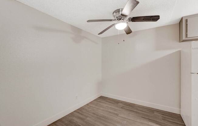 A room with a ceiling fan and wooden flooring.