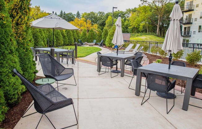 A communal outdoor patio adorned with ample seating arrangements, a cozy gas fireplace, and a fully-equipped grill ready for summer cookouts. The atmosphere radiates warmth and relaxation, offering residents a perfect setting to unwind and socialize amidst the comfort of their living space.
