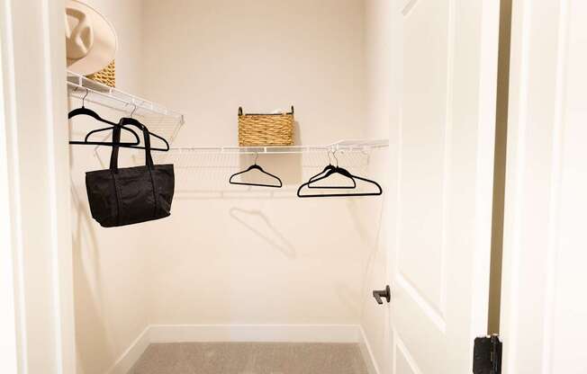 A black bag hanging on a white hanger in a closet.