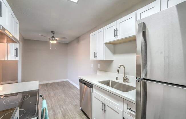 A kitchen with a stove top oven, sink, and refrigerator.