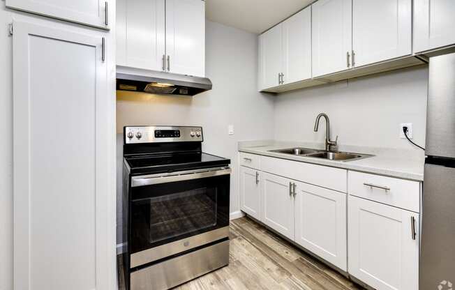 an empty kitchen with white cabinets and stainless steel appliances