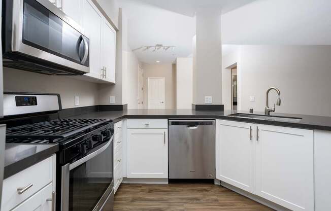A modern kitchen with white cabinets and black countertops.