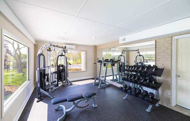 A well lit home gym with a bench, weights and exercise equipment.