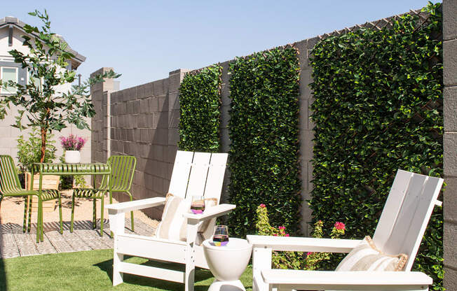 a backyard patio with two chairs and a toilet and a privacy hedge