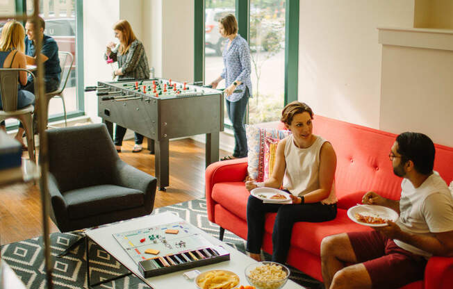 a group of people sitting in a living room next to a foosball table