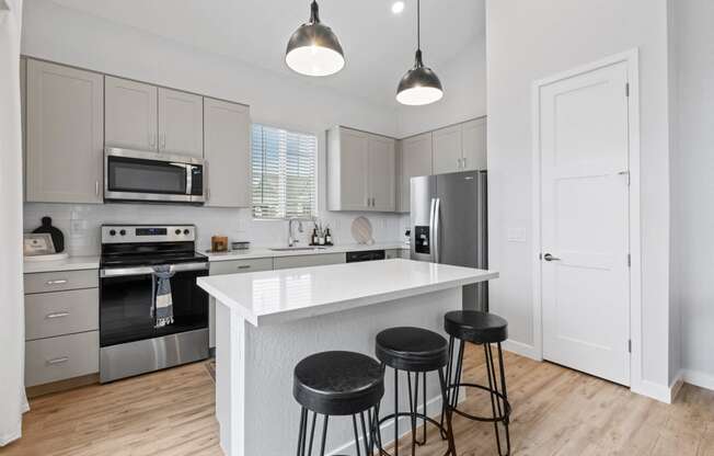 a kitchen with a large island with three stools at Village of Chandler Apartments, Chandler, AZ, 85249