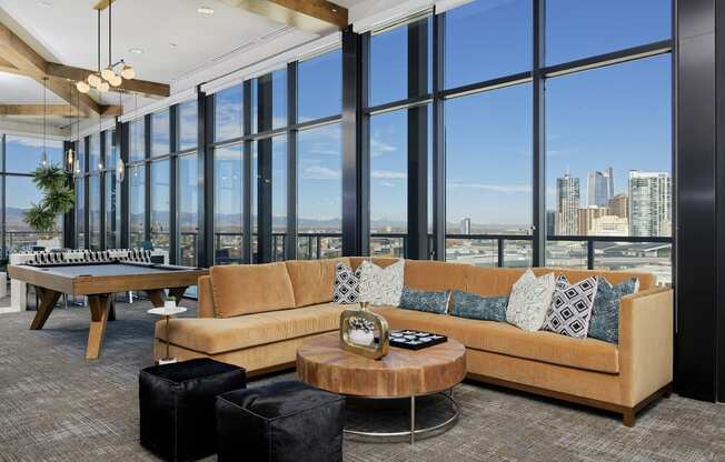 Sky lounge with sectional couch, pool table and large glass windows with view of Denver skyline