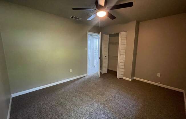 A room with a ceiling fan and carpeted floor.