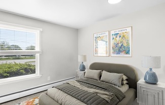 A bedroom with a large bed and two framed pictures on the wall.