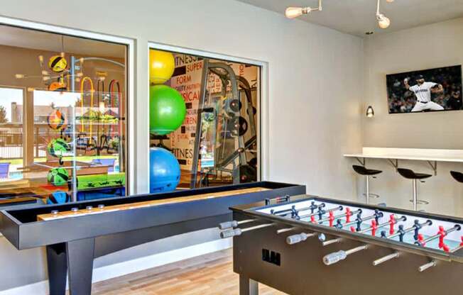 A room with a foosball table and a pool table.