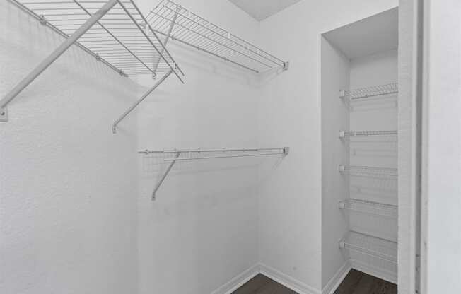 an empty closet in a white room with white walls and metal shelves