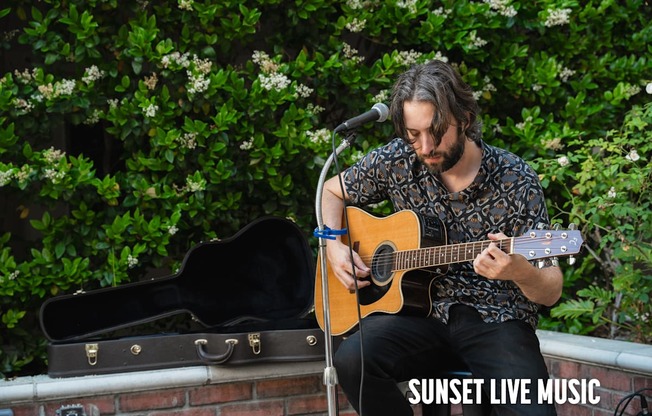 A man playing guitar on a stage with a microphone.