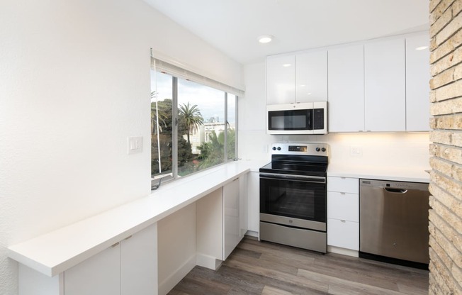 a kitchen with white cabinetry and a large window