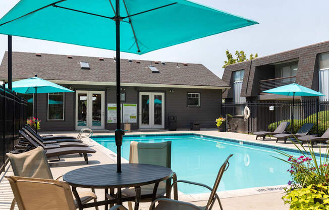 A pool area with a table and chairs and umbrellas.